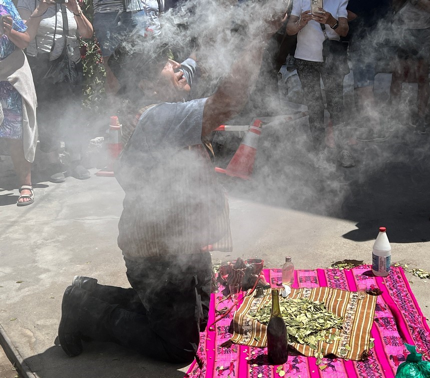 Shaman performing a ritual with smoke, coca leaves, and wine.