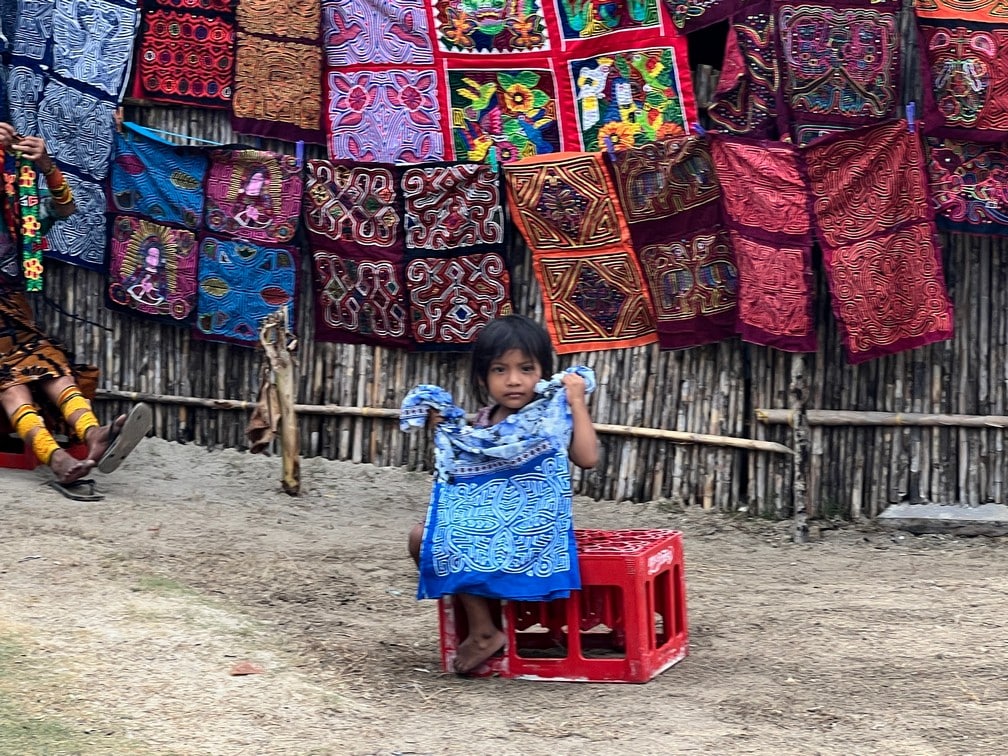 A Kuna child offering one of thousands of tapestries made for tourists